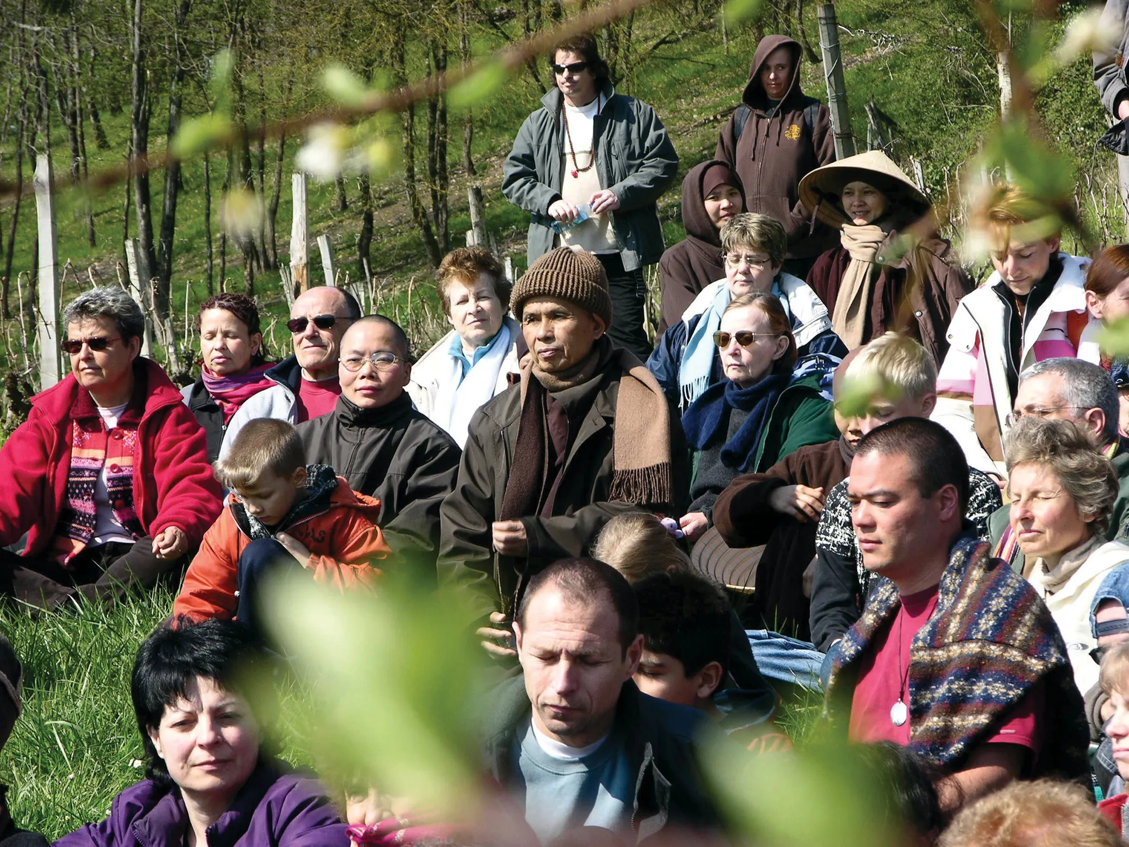 Pratiquants assis dans l’herbe autour de Thich Nhat Hanh, au printemps